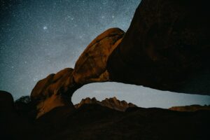 Rock arch under a starry night sky